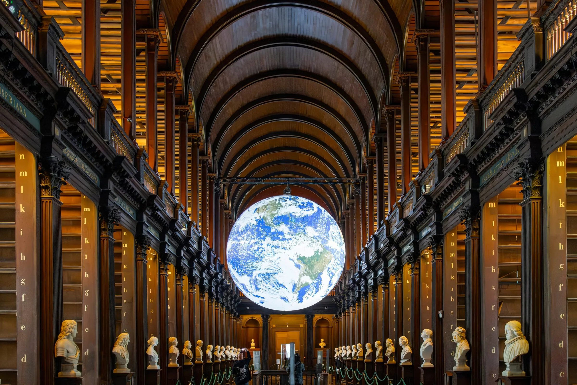 The long room of a historic university library, barrel-vaulted and lined with shelves.